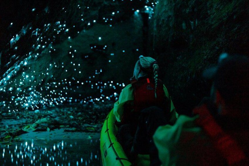 A person in a yellow kayak navigating a narrow, rocky waterway at night. 1