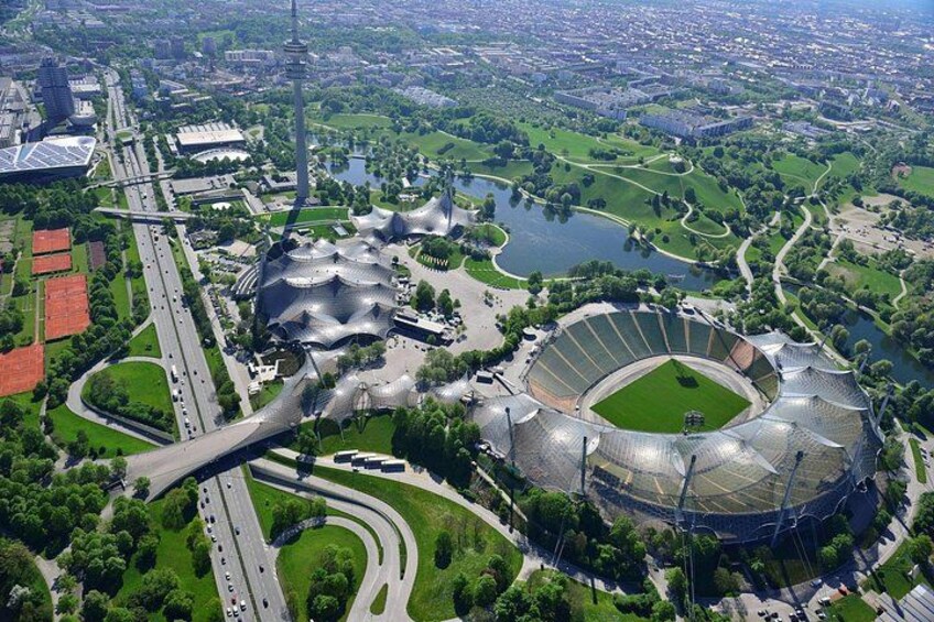 An aerial view of a city with a large stadium, a river, and surrounding greenery. 5