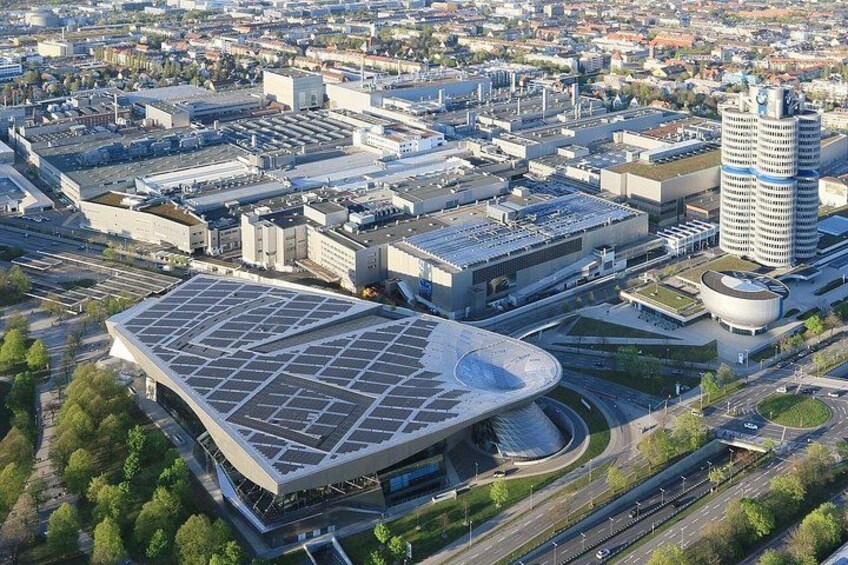 An urban landscape with a large, modern building with a curved roof, surrounded by smaller buildings and roads. 4