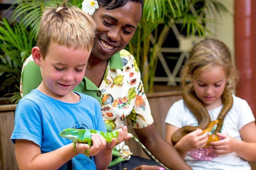 A person holding a green lizard, another holding a bottle, and a child in a white shirt. 3