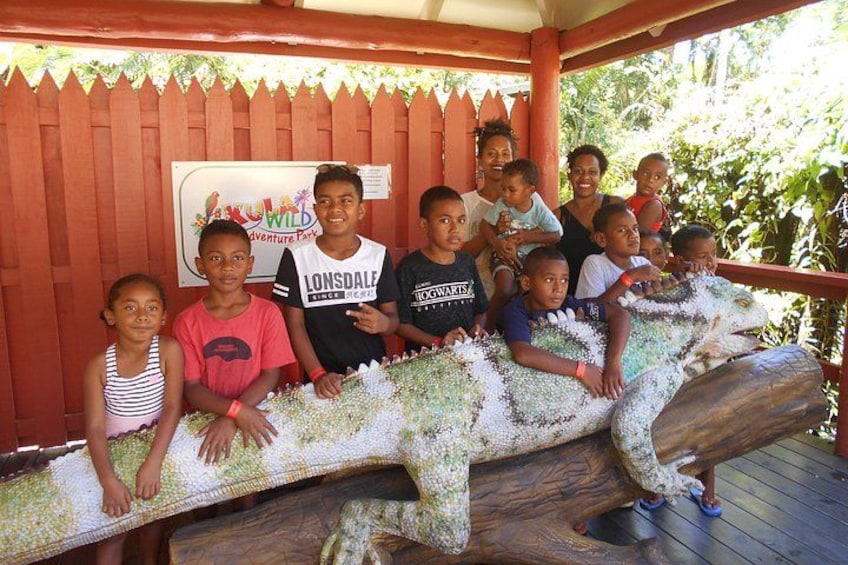 Eine Gruppe von Menschen posiert vor einer großen Krokodils-Skulptur. 2