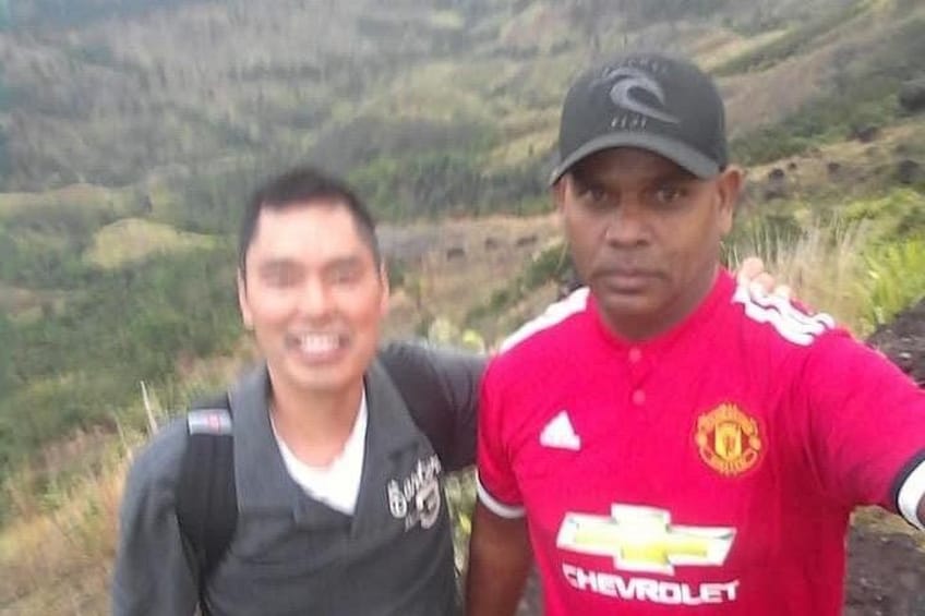 Two individuals outdoors with a mountainous landscape in the background. 3