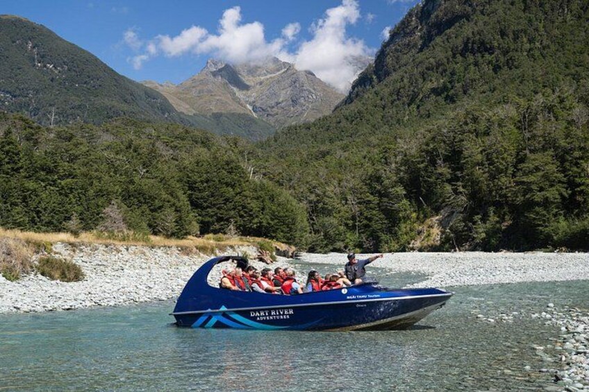 Ein blaues Boot mit Passagieren auf einem Fluss, umgeben von Bergen. 4