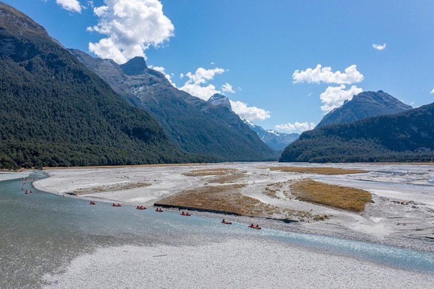 Un río con barcos, rodeado de montañas y un cielo despejado. 2
