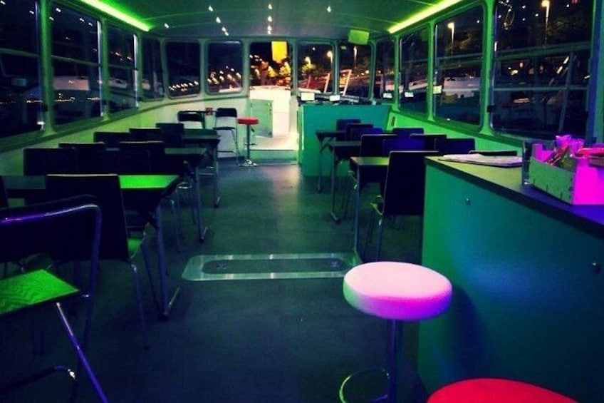 A dimly lit bar area with tables and stools, large windows, and a counter. 5