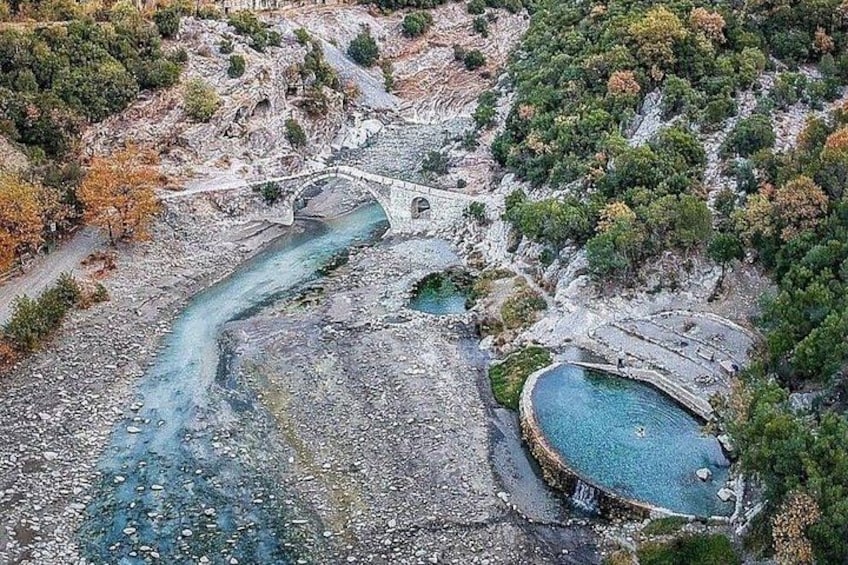Un río, un puente y una piscina rodeados de terreno rocoso y árboles. 3