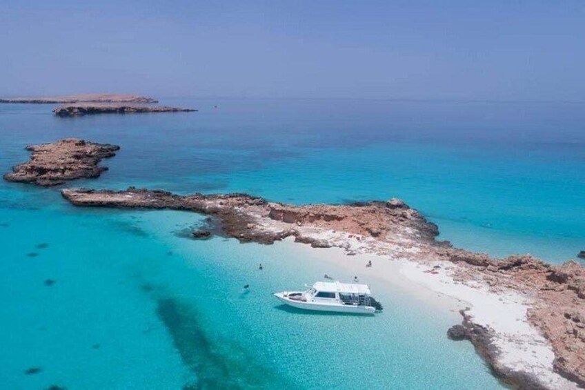 A boat near a rocky shoreline with clear turquoise water. 1