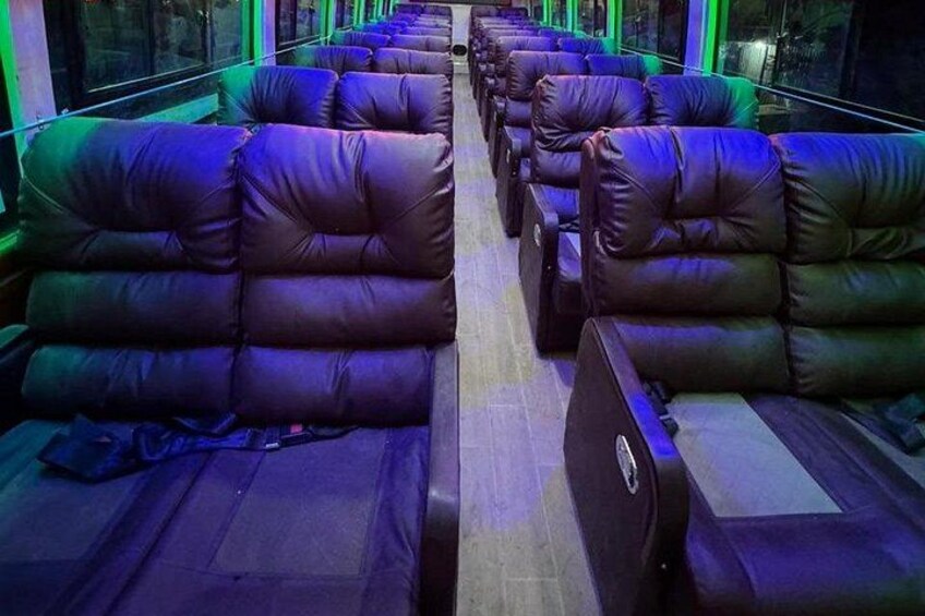 Rows of leather seats with a wooden floor and windows. 5