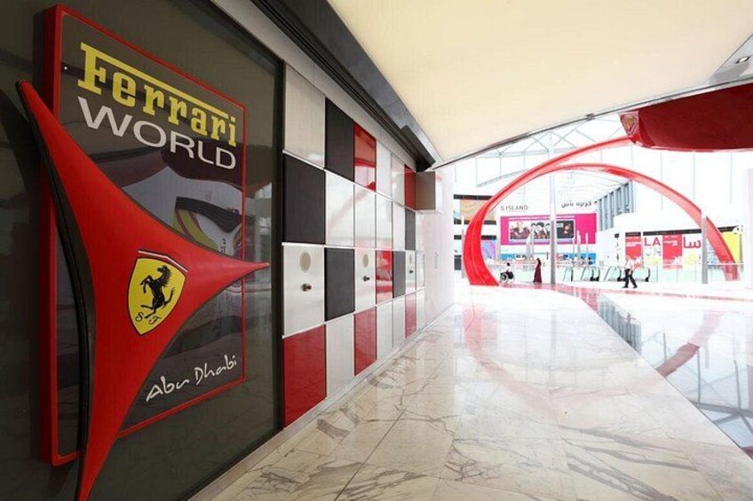 A corridor with a Ferrari World sign, a checkered pattern wall, and a red archway. 2
