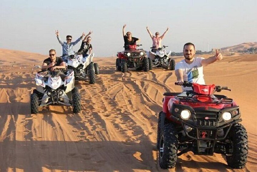 Quattro persone che guidano quad attraverso un sentiero sabbioso nel deserto. 1