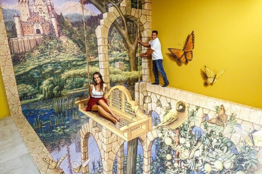 A mural with a castle, a woman on a swing, and butterflies on a yellow wall. 2