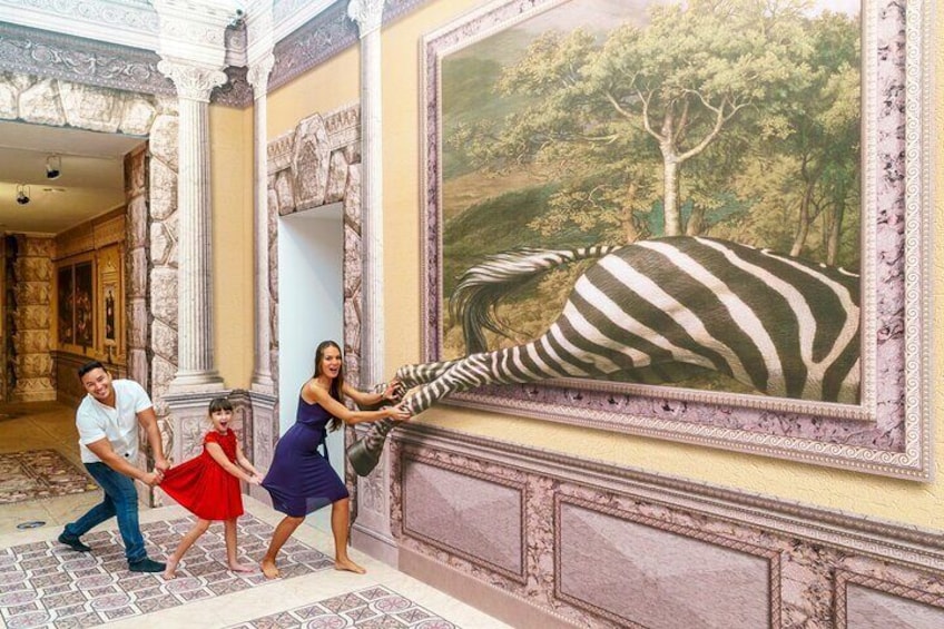 A family interacting with a large zebra mural in a room with ornate columns and a patterned floor. 4
