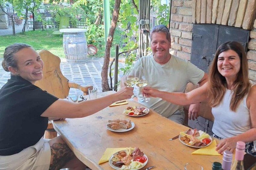 A group of people toasting with wine glasses at a wooden table with food. 2