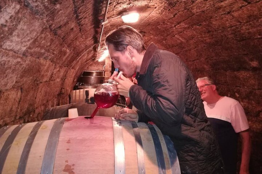 A person pouring wine from a barrel into a glass. 3