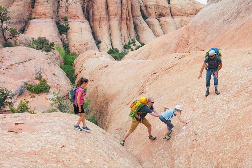 A group of hikers on a rocky trail with large boulders and sparse vegetation. 5