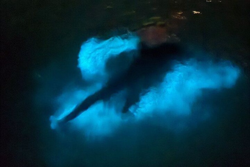 A person swimming in a body of water with blue light effects. 4