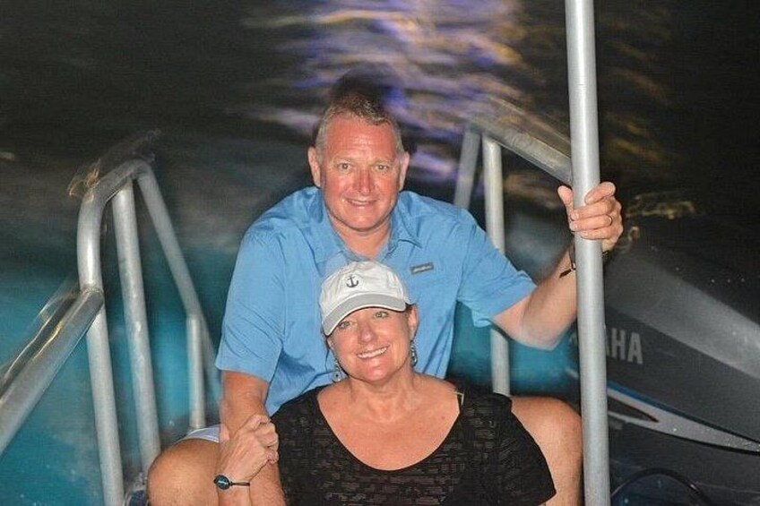 A person in a black swimsuit sitting on a pool ladder, with another person in a blue shirt standing behind them. 5