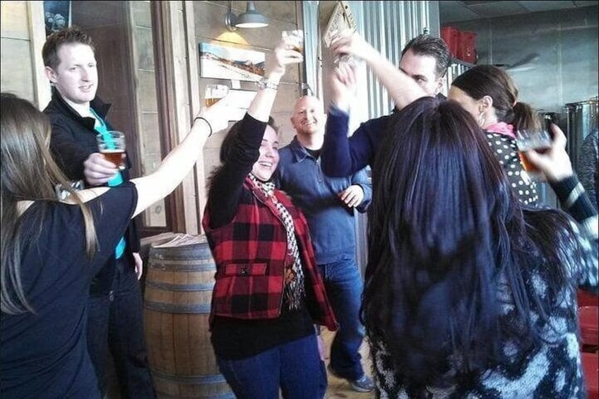 A group of people toasting with drinks in a bar setting. 2