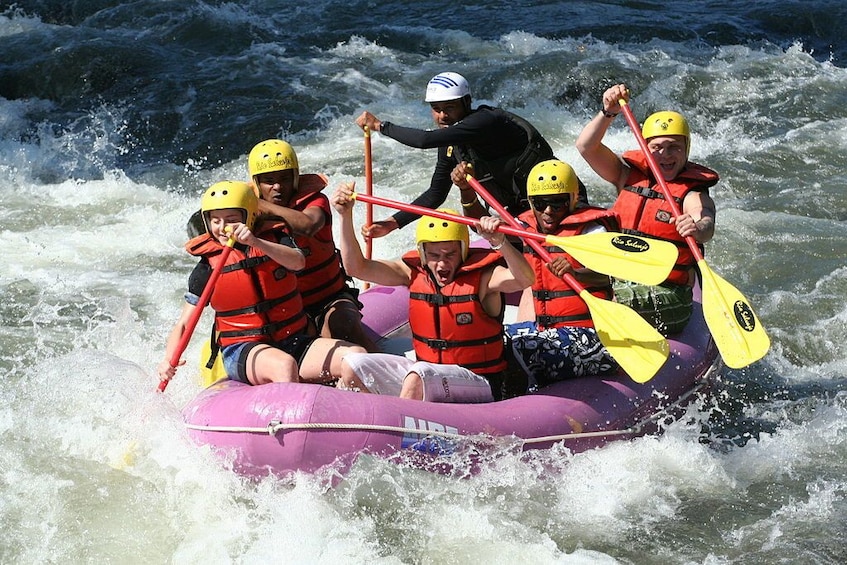 A group of people in a raft navigating through rough waters. 1