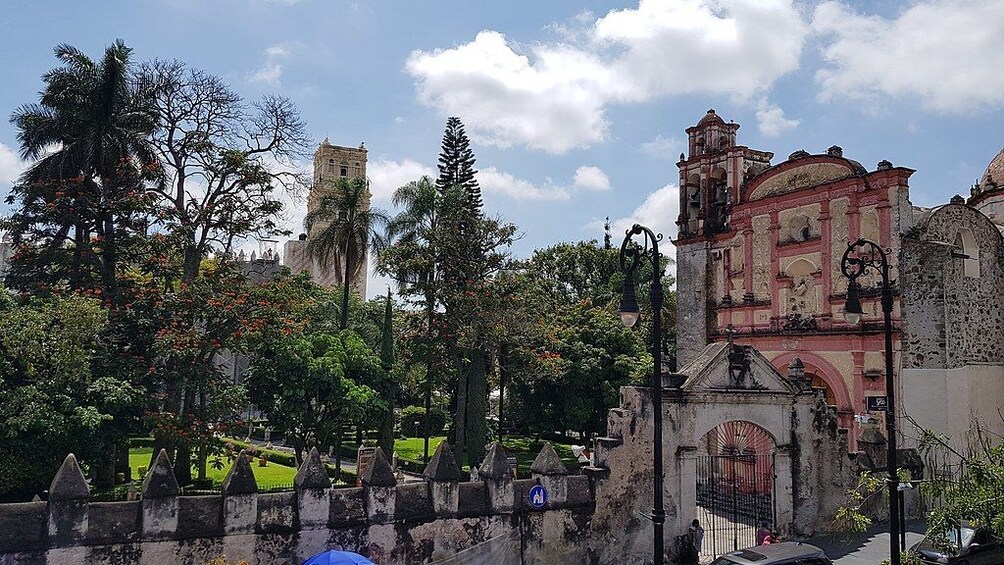 A historic building with a bell tower, surrounded by trees and a well-maintained garden. 2