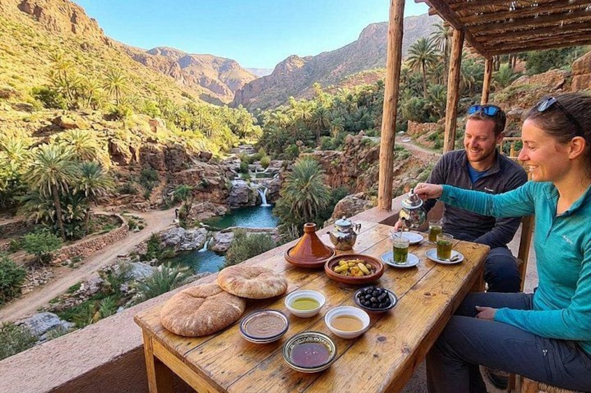 A couple dining outdoors with a view of a canyon and a river. 2