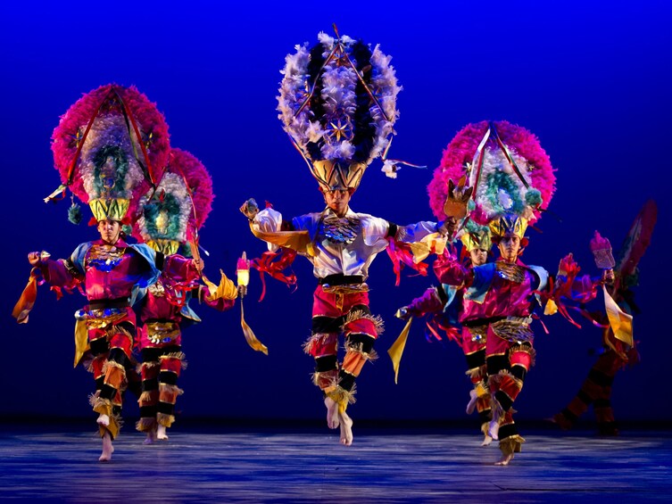 Performers in colorful costumes with elaborate headdresses and props. 1