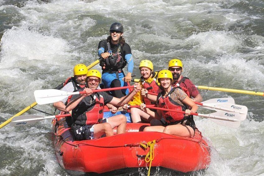 A group of people in a red inflatable raft on a river with rapids. 3