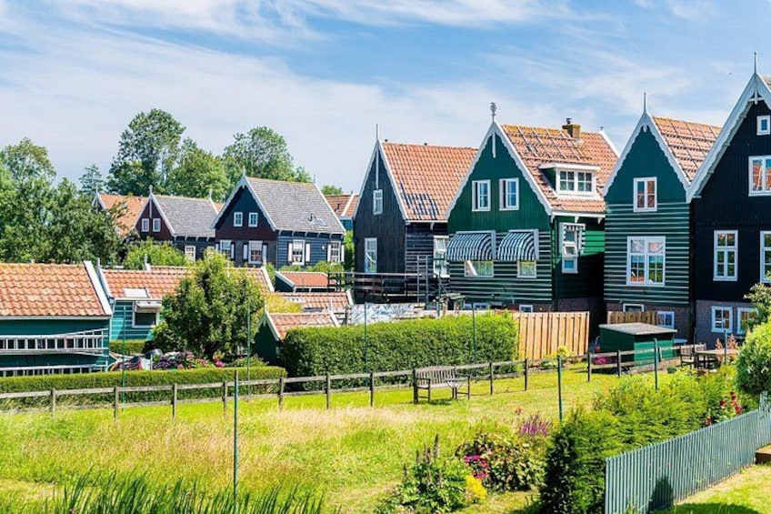 A row of traditional houses with steep roofs, a grassy field, and a clear sky. 2