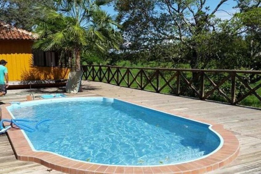 Una piscina con cubierta de madera, rodeada de una valla y palmeras. 4