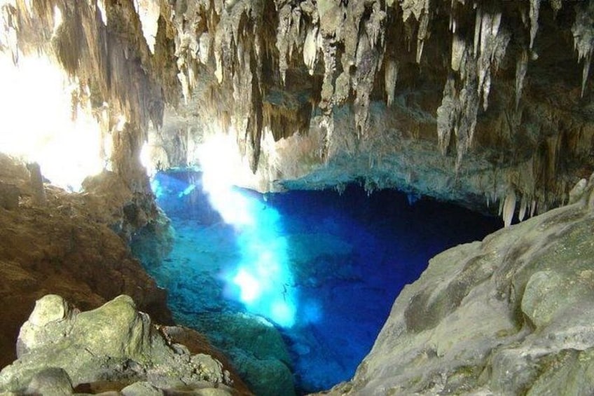 Una cueva con estalactitas y una poza azul. 3