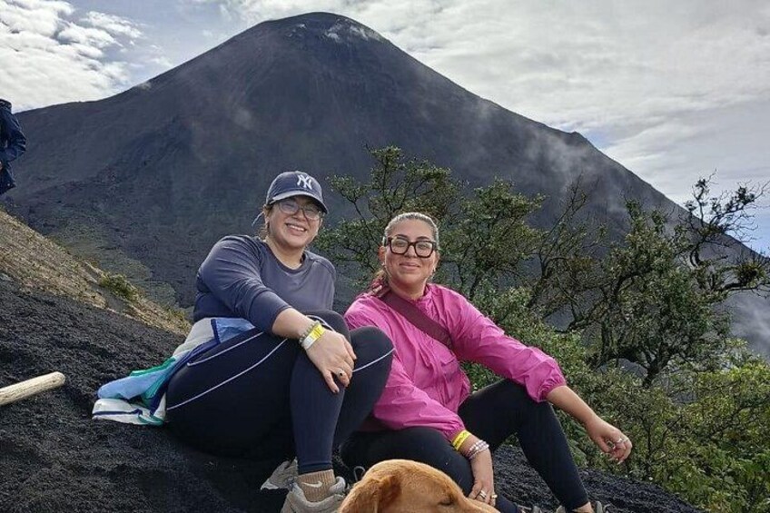 Dos personas sentadas en una pendiente con una montaña al fondo. 5