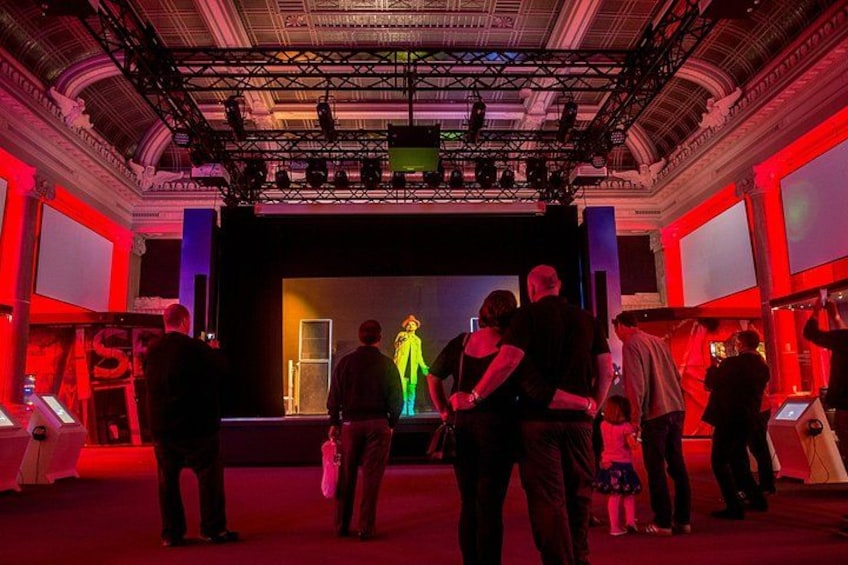 Un grupo de personas en un evento interior con un escenario y un fondo iluminado en rojo. 2