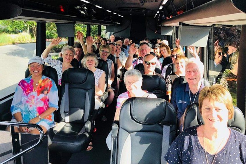 Un groupe de personnes est assis à l’intérieur d’un autobus, et certaines lèvent la main. 3