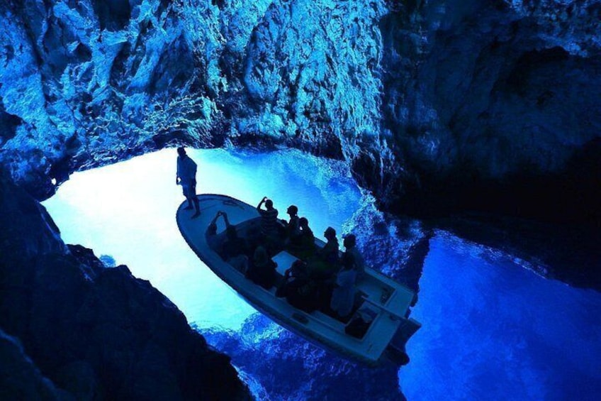 A boat tour inside a cave with a guide leading the group. 1