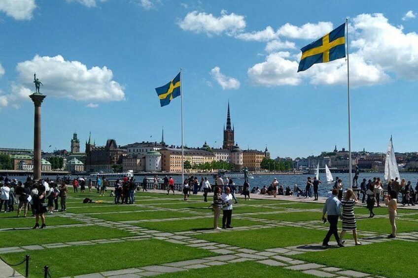 A public square with flags, a statue, and a river in the background. 1