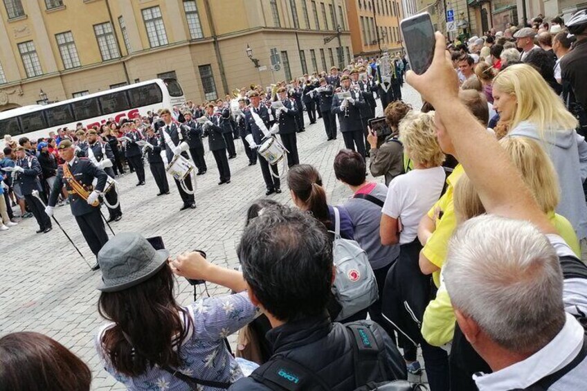 A marching band performing in a public square with an audience watching. 4