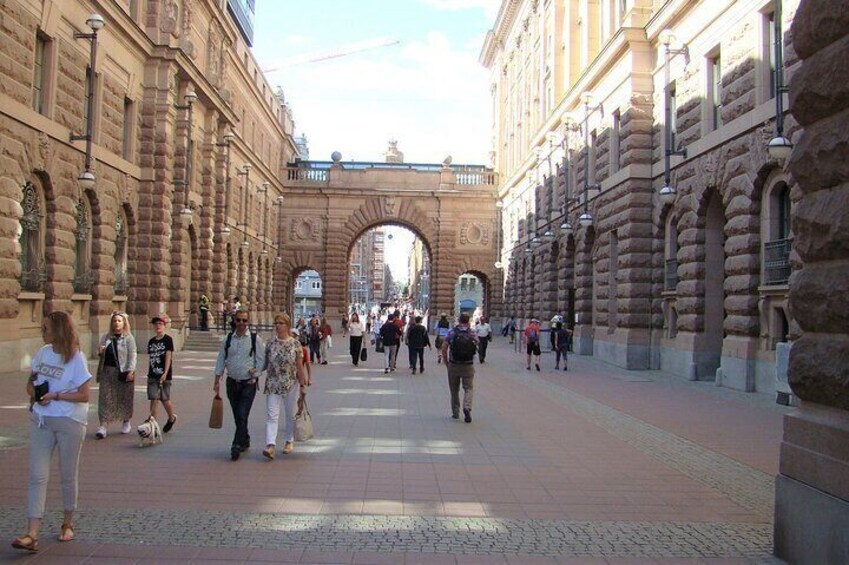A pedestrian street with stone buildings and an archway. 2