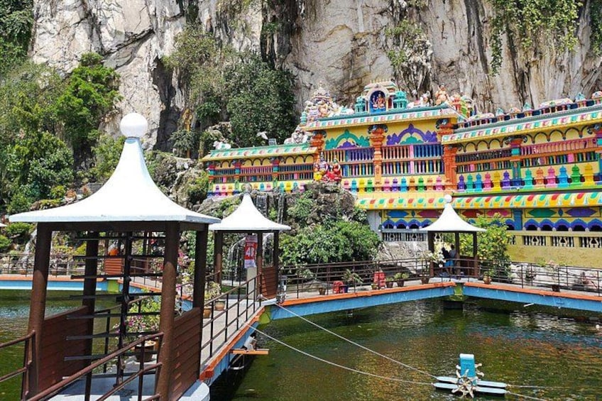 Un templo colorido con una masa de agua en primer plano, rodeado de acantilados rocosos. 5