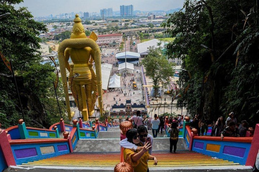 Una estatua dorada de gran tamaño en la parte superior de una escalera con barandas de colores. 2