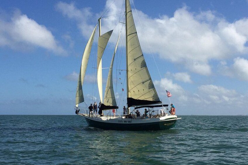 Een zeilboot met verschillende zeilen op een kalme zee onder een lichtbewolkte lucht. 2