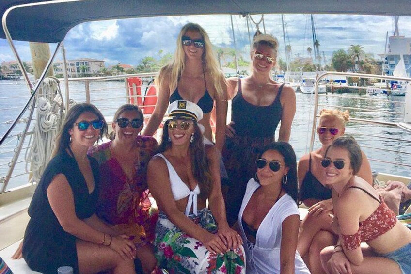 Een groep mensen op een boot, met een jachthaven en boten op de achtergrond. 5