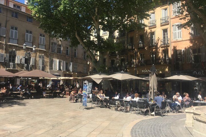 Een terras met tafels en parasols, omringd door gebouwen. 4