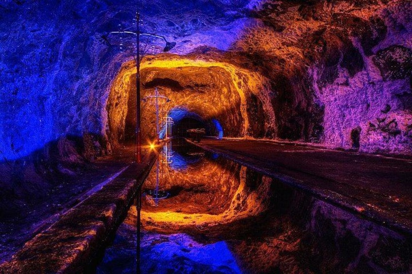 A tunnel with a glowing light source at the end, surrounded by rocky walls. 1