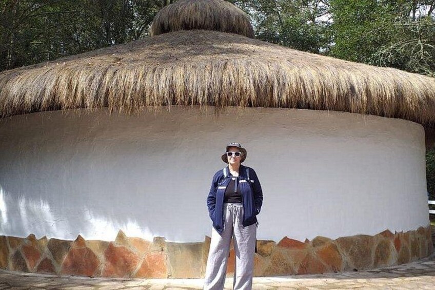 A person standing in front of a large, round, white structure with a thatched roof. 5