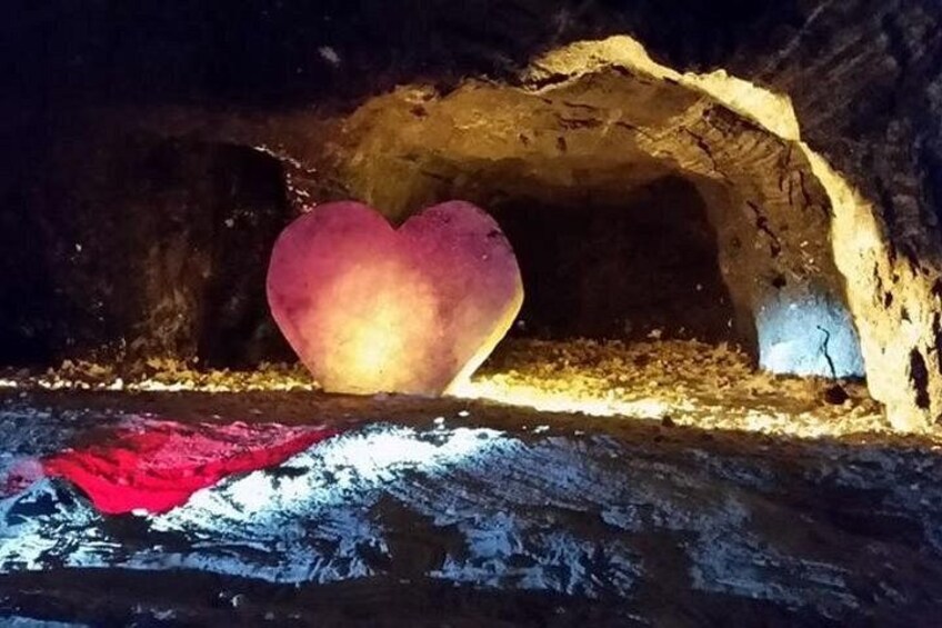 A cave with a heart-shaped rock formation illuminated by artificial light. 3