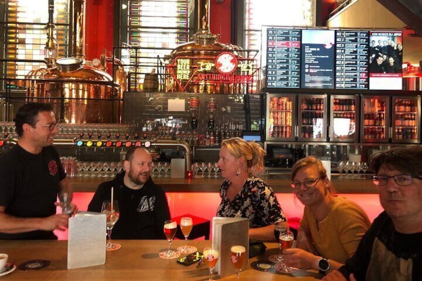 A group of people sitting at a bar with a menu and glasses of beer. 2