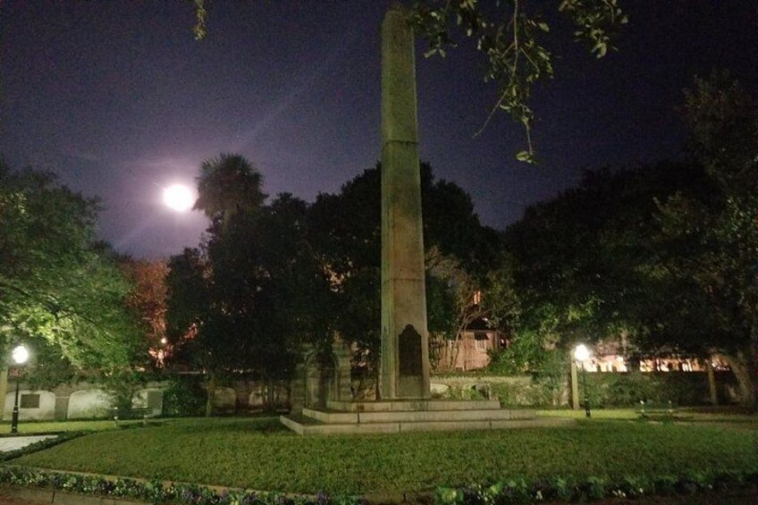 A tall monument in a park at night with a full moon in the background. 2