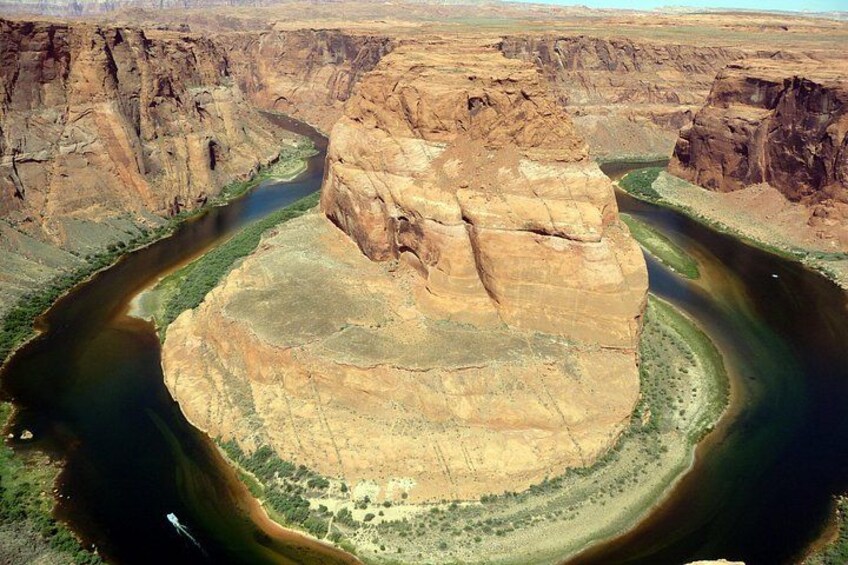 A large rock formation surrounded by a river. 3