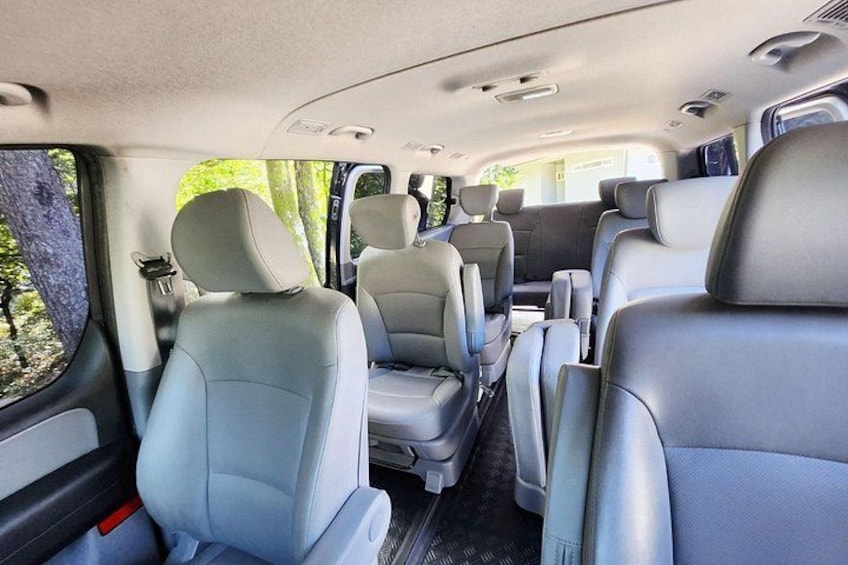 A vehicle interior with multiple seats, a center console, and a window on the side. 2