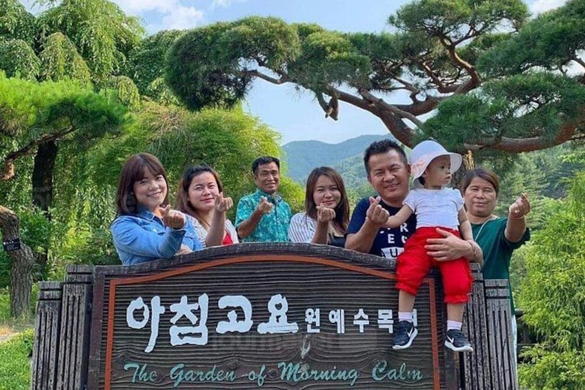 A group of people standing in front of a sign with Korean text and English translation. 5